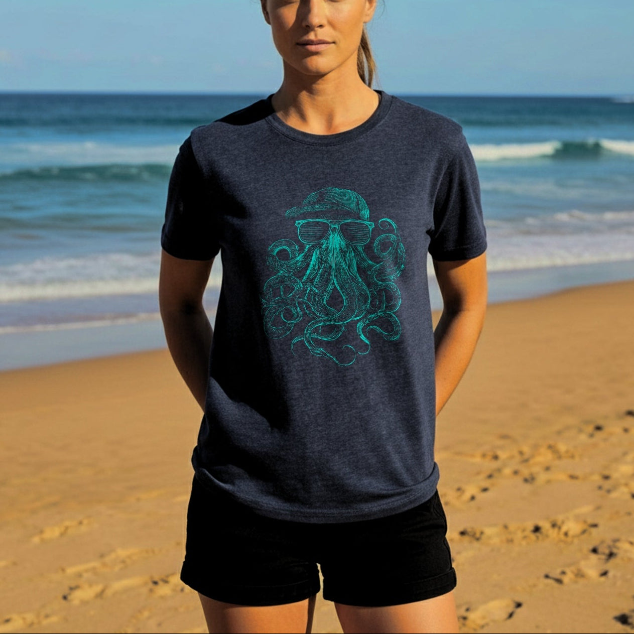 Woman wearing a dark blue t-shirt with a green octopus design on a beach.