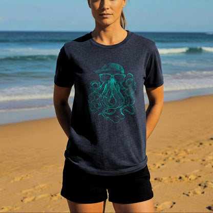 Woman wearing a dark blue t-shirt with a green octopus design on a beach.