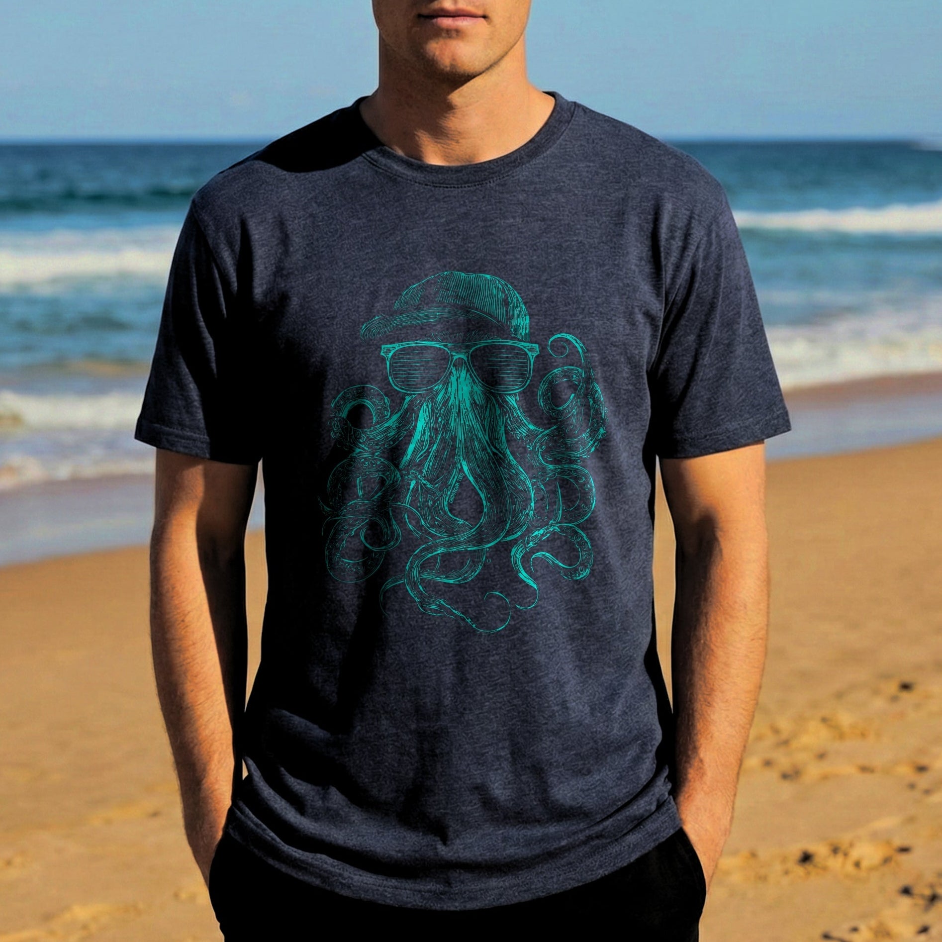 Man wearing a dark blue t-shirt with a green octopus design on a beach.