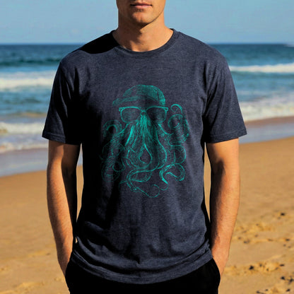 Man wearing a dark blue t-shirt with a green octopus design on a beach.