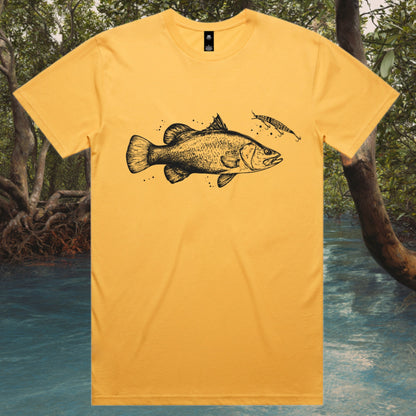 Yellow t-shirt with a Barramundi fish design in front of a natural mangrove creek background