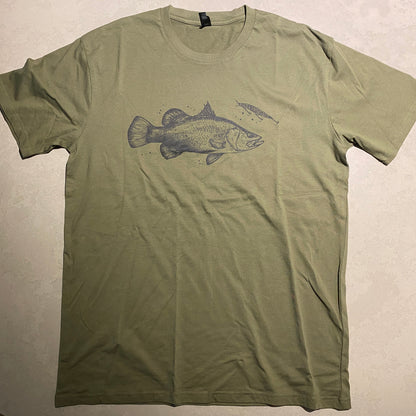 An olive green short-sleeve t-shirt laid flat on a light-colored surface, featuring a dark gray graphic of a barra fish on the chest.