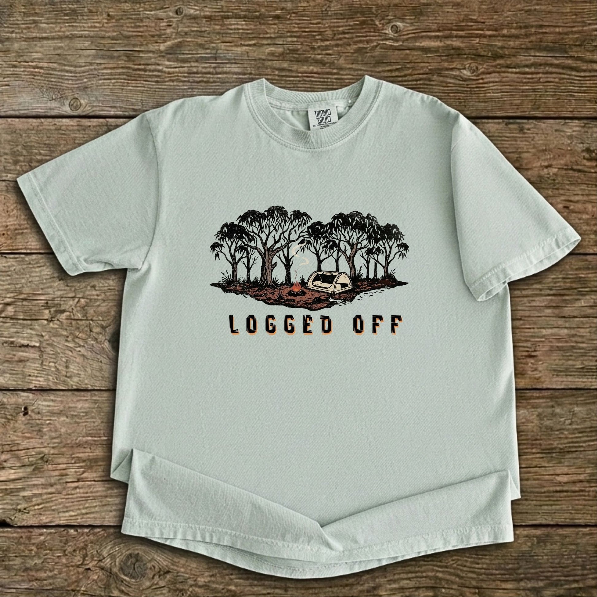 Logged Off camping shirt, t-shirt with a detailed screen-printed design of a smoking campfire and a dome tent nestled among towering Ghost Gums in the Australian bush.