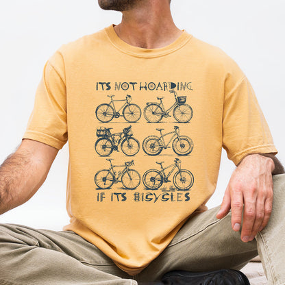 A man wearing a mustard yellow graphic t-shirt with a black bicycle design and the text 'ITS NOT HOARING IF ITS BICYCLES'.