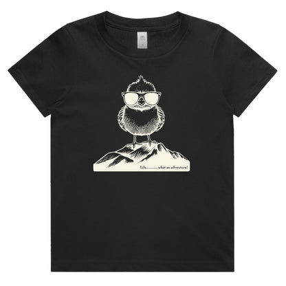 A black short-sleeve crewneck t-shirt featuring a white line art graphic of a bearded figure wearing sunglasses and a mountain, with the text 'What is adventure' printed below.
