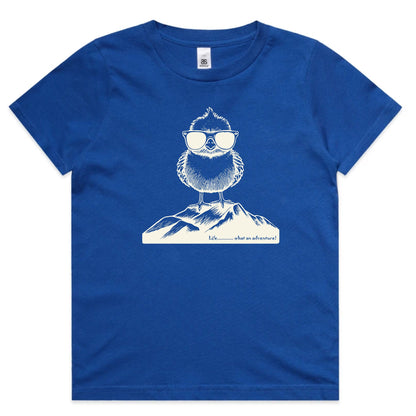 A royal blue short-sleeve crewneck t-shirt featuring a white line art graphic of a bearded owl wearing sunglasses perched on a mountain range, with the text 'I'll be there in a minute!' printed below.