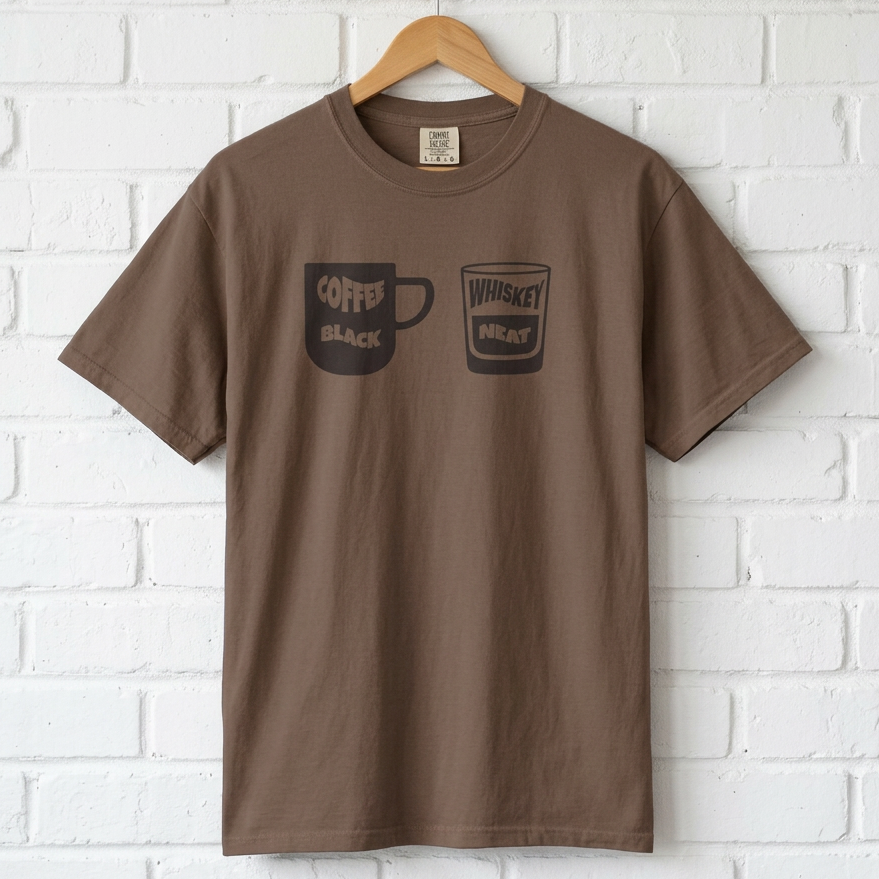 Brown t-shirt with coffee and whiskey graphic on a hanger against a white brick wall.