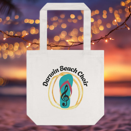 White tote bag with 'Darwin Beach Choir' logo against a blurred bokeh background