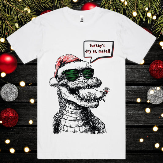 White t-shirt with a crocodile eating a turkey wearing a Santa hat and sunglasses.