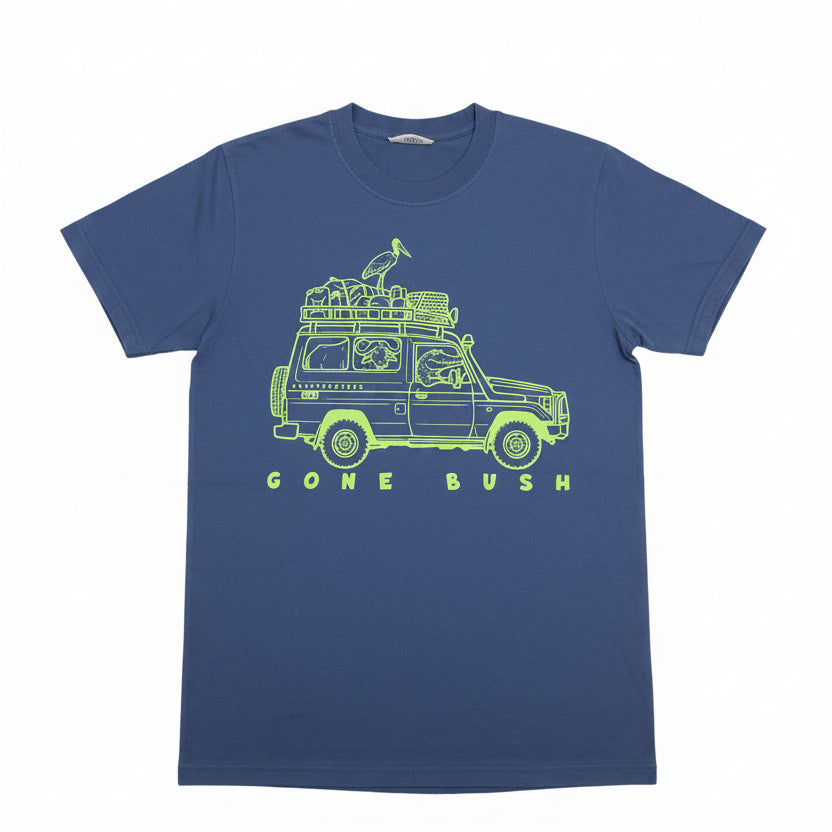 A blue short-sleeve t-shirt with a lime green graphic of a safari jeep carrying a bird on its roof rack, with the text 'GONE BUSH' printed below. The shirt is laid flat on a textured beige background with a paper tag attached to the collar.