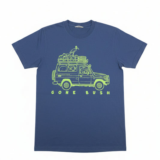 A blue short-sleeve t-shirt with a lime green graphic of a safari jeep carrying a bird on its roof rack, with the text 'GONE BUSH' printed below. The shirt is laid flat on a textured beige background with a paper tag attached to the collar.