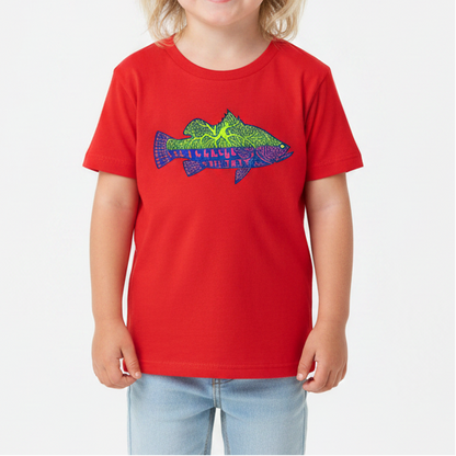 A young child with blonde hair stands against a white studio background wearing a bright red short-sleeve t-shirt with a colorful fish graphic on the chest, light blue denim shorts, and white sneakers.