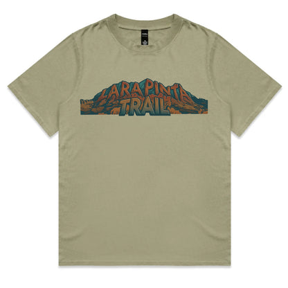 An olive green short-sleeve t-shirt with a graphic print on the chest reading 'LARAPINTA TRAIL' in stylized orange and blue lettering over a mountain illustration, displayed flat against a white background.