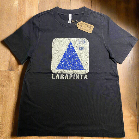 Black stone washed womens t-shirt with graphic white square and blue triangle and 'Larapinta' text on a wooden table.