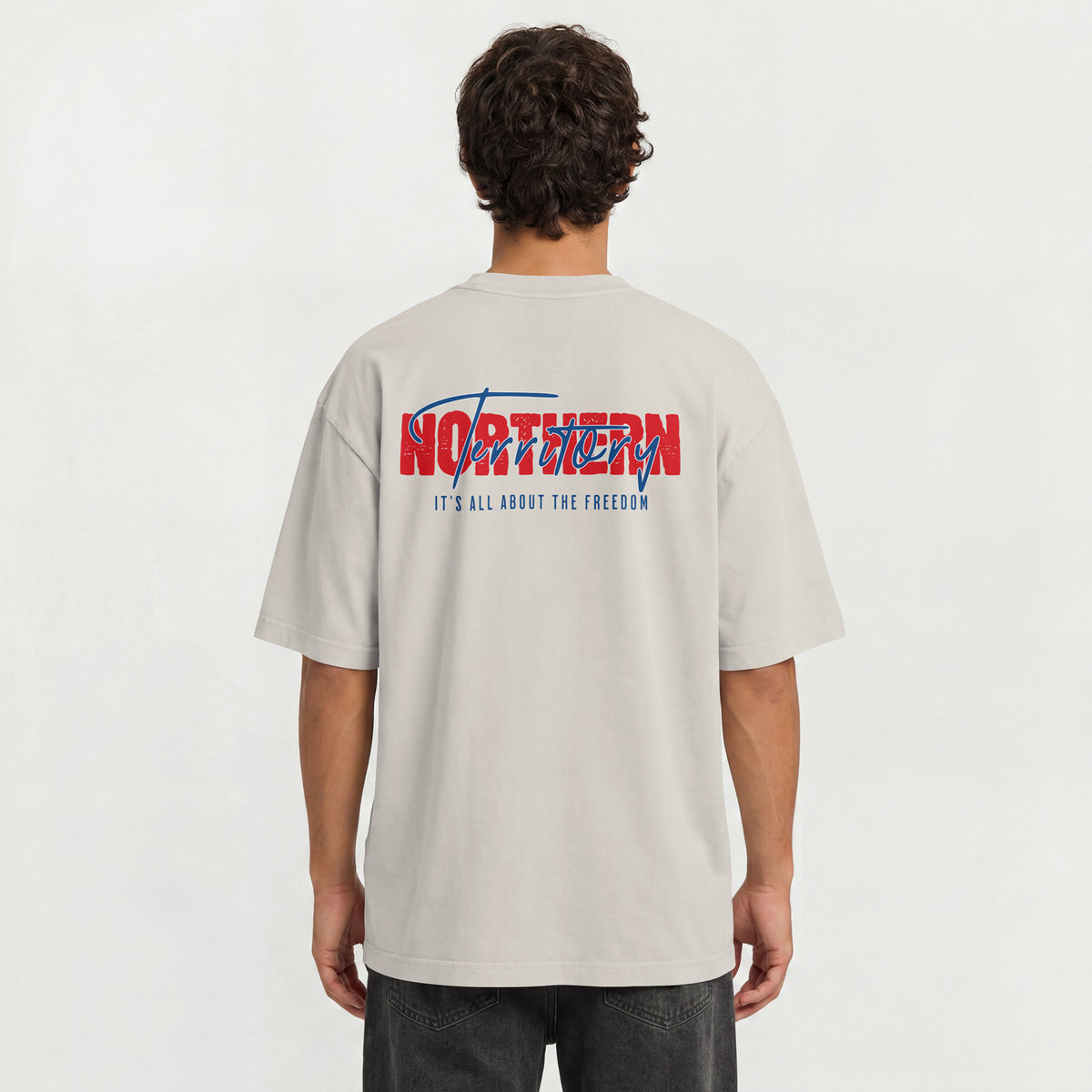 A man viewed from behind wearing a light beige t-shirt with a large red and blue graphic on the back that reads 'NORTHERN Territory IT'S ALL ABOUT THE FREEDOM'.