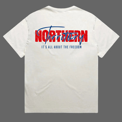 An off-white crewneck t-shirt shown from the back, featuring a graphic print with the word 'NORTHERN' in distressed red block letters and 'Territory' in blue script, with the slogan 'IT'S ALL ABOUT THE FREEDOM' printed below in blue.