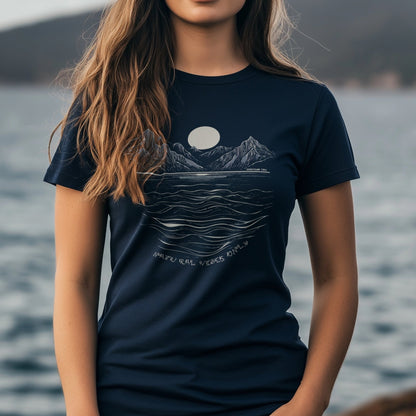 A Woman wearing a Navy Maple Tee Womens Fit T-Shirt witha beautiful print of Mountains and Sea with the text "Natural Vibes Only" printed below. The T-Shirt is Navy and the print is off white. There is a background of mountains and sea.