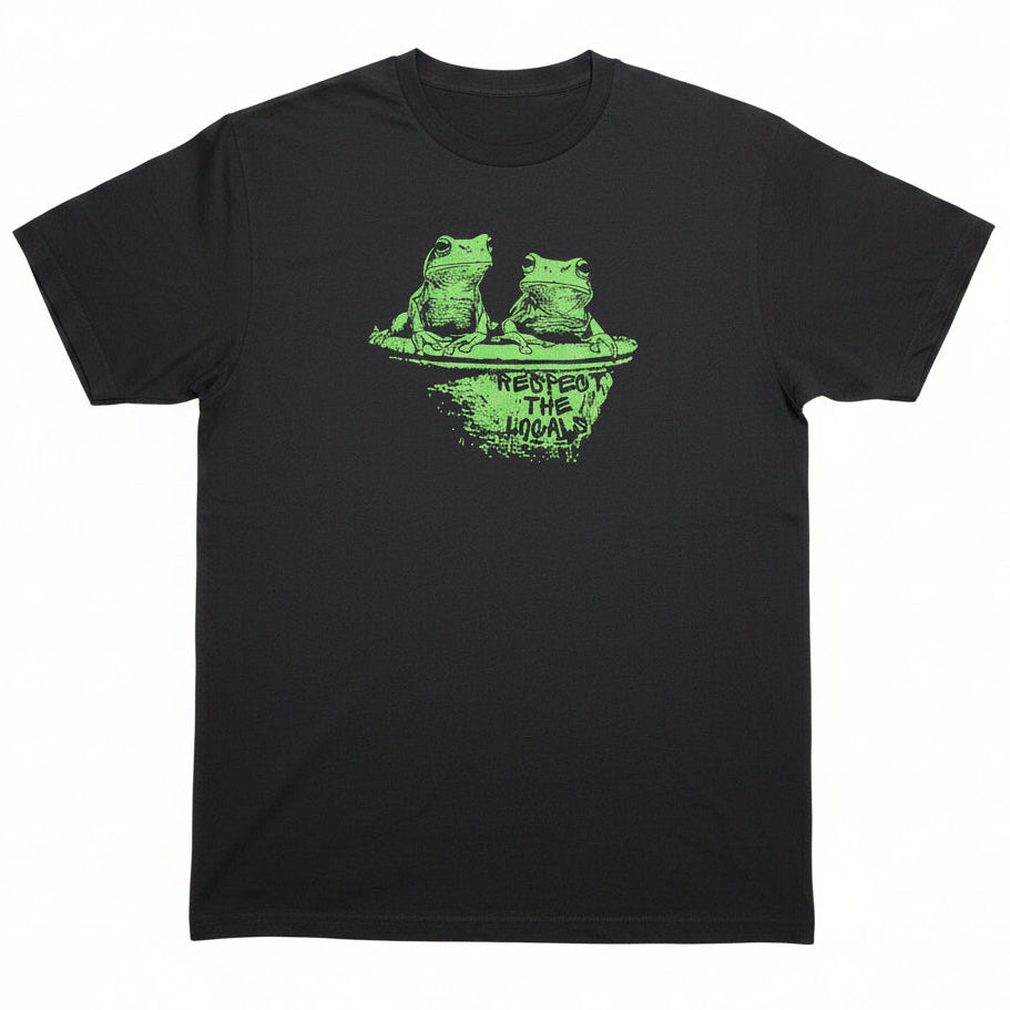 A black short-sleeve graphic t-shirt laid flat on a light-colored surface. The shirt features a green distressed graphic of a green tree frog on a toilet with the text 'Respect the Locals' printed below it.