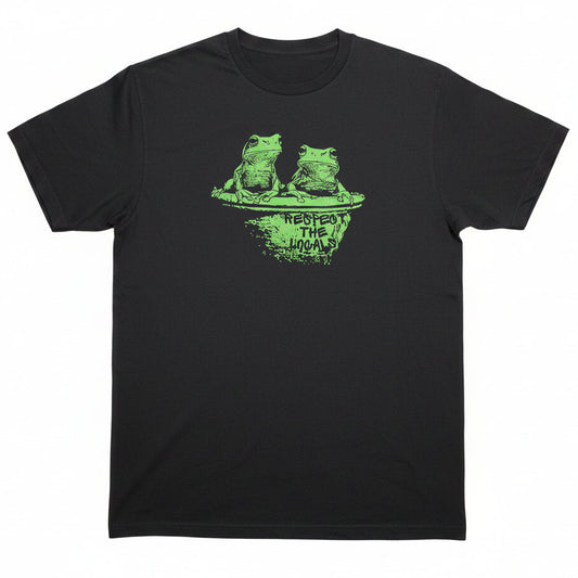 A black short-sleeve graphic t-shirt laid flat on a light-colored surface. The shirt features a green distressed graphic of a green tree frog on a toilet with the text 'Respect the Locals' printed below it.