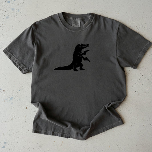 A dark gray short-sleeve t-shirt with a black silhouette of a walking alligator printed on the center chest, displayed flat against a white background.