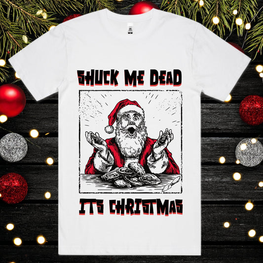 White t-shirt with a graphic of Santa Claus and text 'Shuck Me Dead It's Christmas' on a festive background.