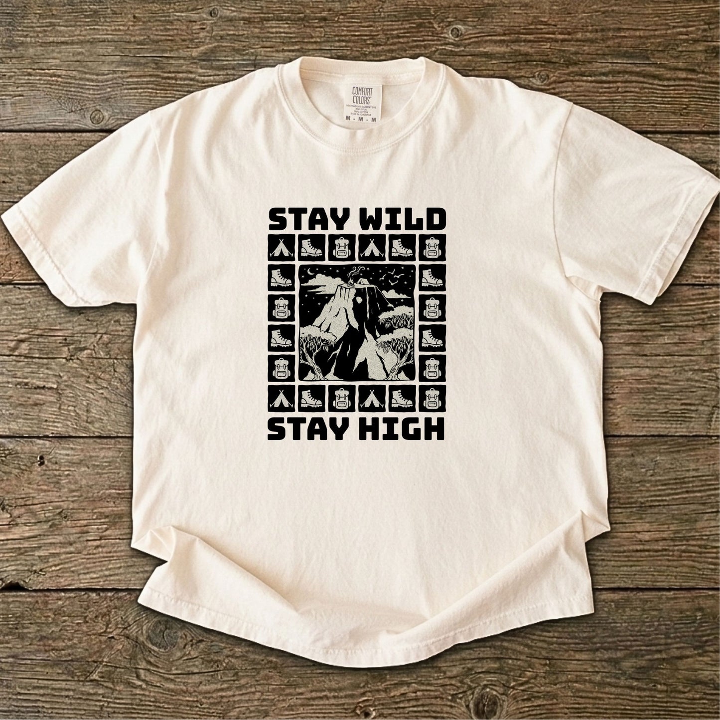 Folded cream-colored t-shirt with 'Stay Wild Stay High' graphic design on a white background