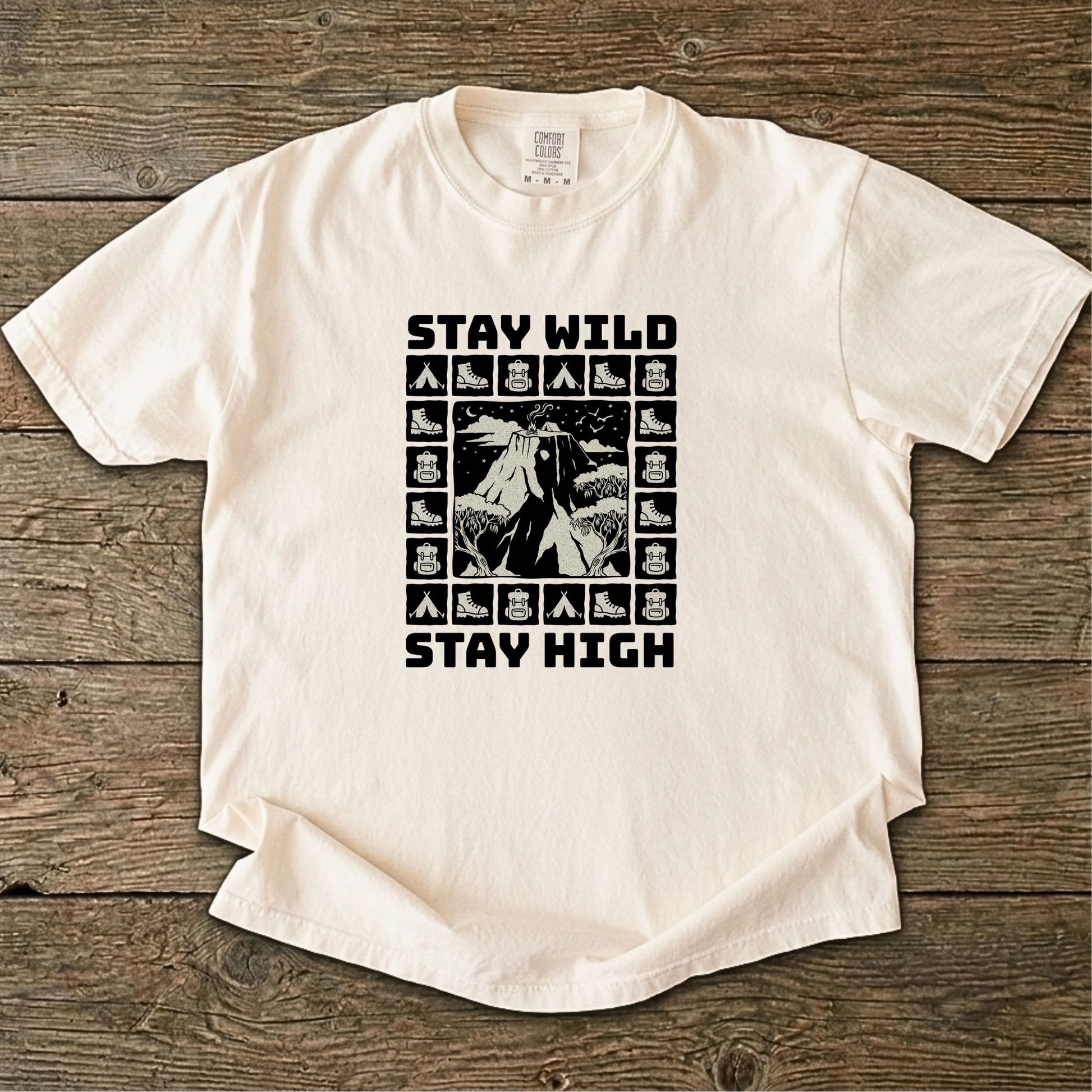 Folded cream-colored t-shirt with 'Stay Wild Stay High' graphic design on a white background