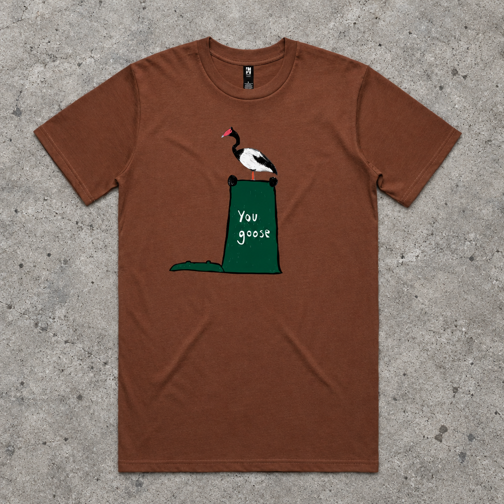 A brown short-sleeve crewneck t-shirt featuring a graphic of a black and white goose with a red beak perched on top of a green trash can containing the text 'you goose'.