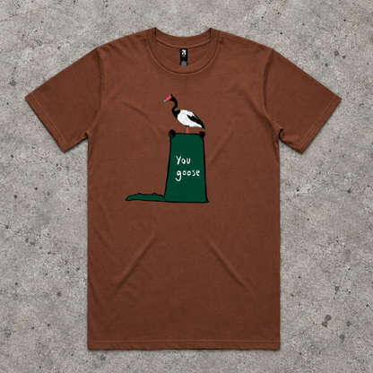A brown short-sleeve crewneck t-shirt featuring a graphic of a black and white goose with a red beak perched on top of a green trash can containing the text 'you goose'.