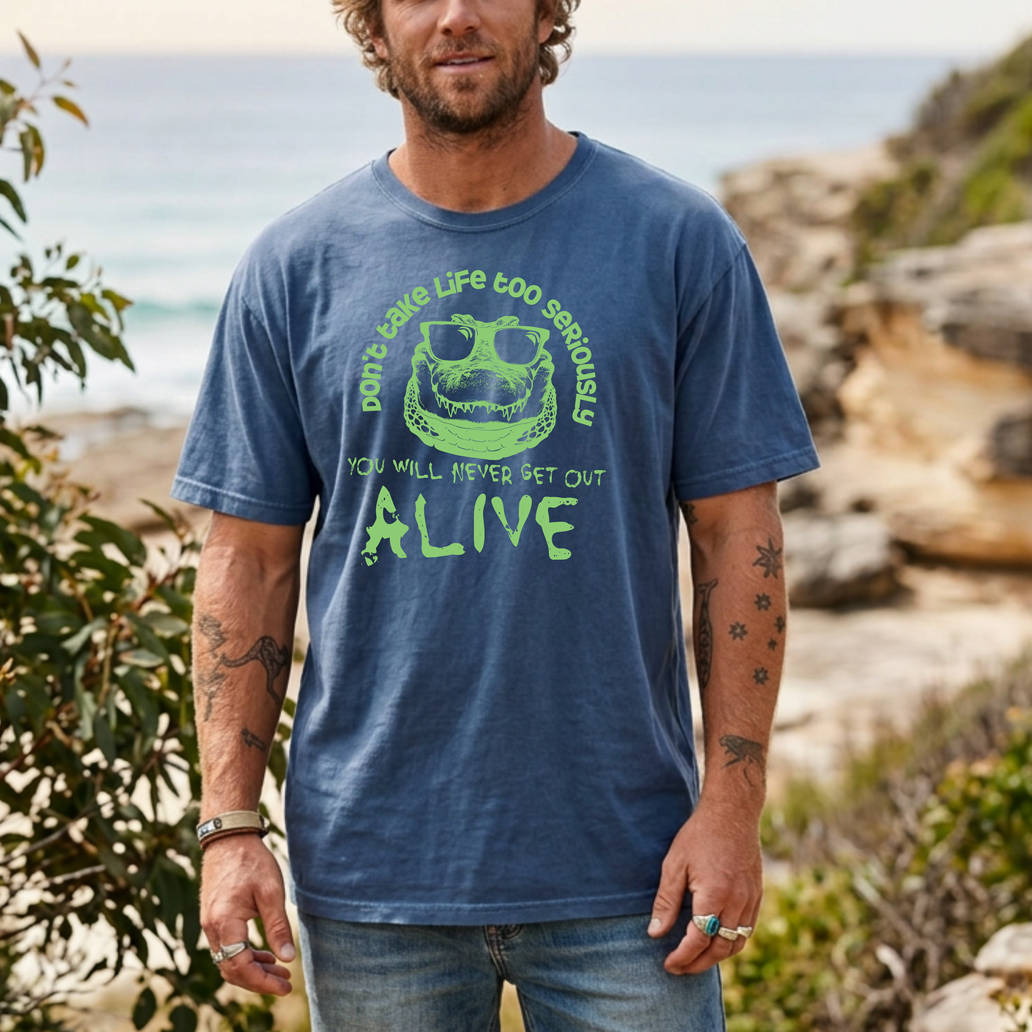 Crocodile T-shirt featuring a green sunglasses-wearing crocodile graphic with the quote “Don’t take life too seriously, you will never get out alive” on a blue tee.