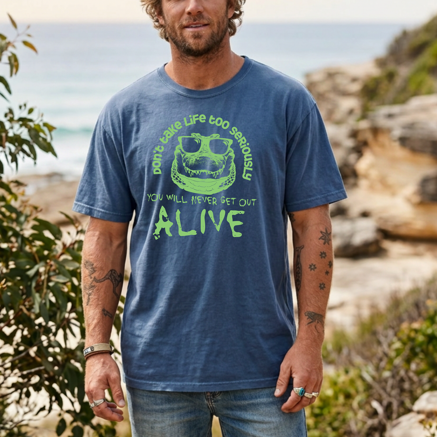 Crocodile T-shirt featuring a green sunglasses-wearing crocodile graphic with the quote “Don’t take life too seriously, you will never get out alive” on a blue tee.