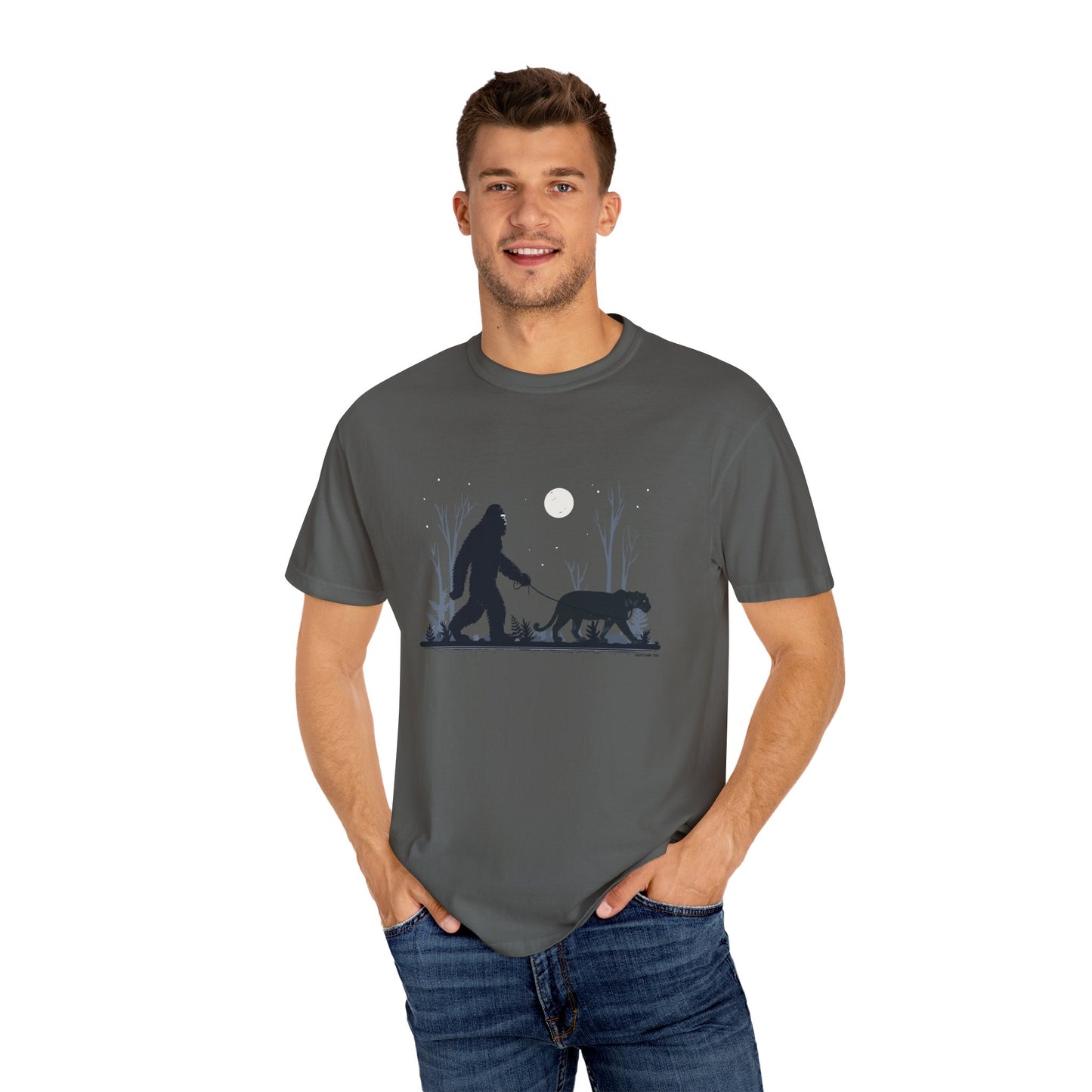 Man wearing a gray t-shirt with a graphic design of a Yowie Bigfoot and Panther walking under a moonlit sky.