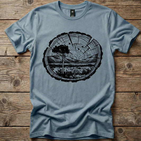 Slate blue Ghost Gum Tees t-shirt featuring a black wood slice graphic containing an Australian outback landscape, a Larapinta gum tree, and distant mountains.