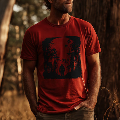 Bigfoot and Yowie T-shirt with dark forest silhouette and full moon design printed on red tee, bold outdoor theme by GhostGum Tees. A man is wearing the TShirt in Mockup Style