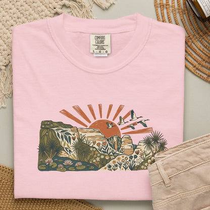 Billabong Sunrise T-shirt featuring an Australian wetland landscape, native plants, rocky escarpment, flying birds and a warm orange sunrise.