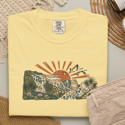 Billabong Sunrise T-shirt featuring an Australian wetland landscape, native plants, rocky escarpment, flying birds and a warm orange sunrise.