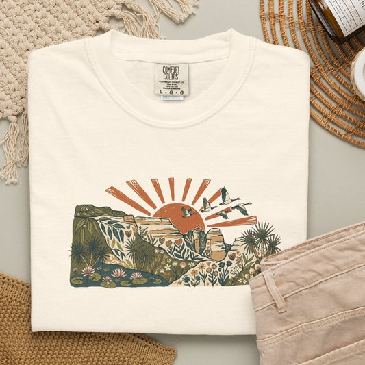 Billabong Sunrise T-shirt featuring an Australian wetland landscape, native plants, rocky escarpment, flying birds and a warm orange sunrise.